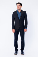 Full body shot of young handsome Persian businessman in suit thinking