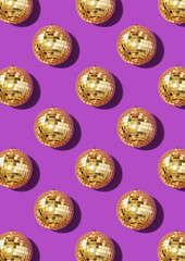 Creative Christmas pattern. Shiny gold disco balls over violet background. Flat lay, top view. New year baubles with shining sparkles. Party time. Cristmas greeting card