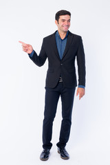 Full body shot of happy young Persian businessman pointing to side and looking away