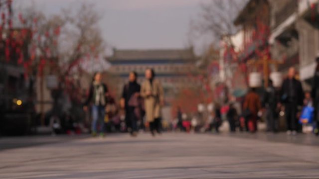 Blurred slow motion view of Qianmen pedestrian street, three women come towards. Famous tourist area of Beijing, shopping and dinning district located on south from Tiananmen square