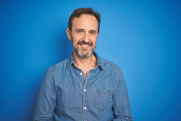 Obraz premium Handsome middle age senior man with grey hair over isolated blue background with hands together and crossed fingers smiling relaxed and cheerful. Success and optimistic