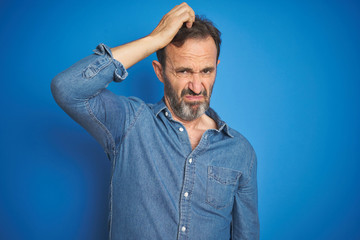 Handsome middle age senior man with grey hair over isolated blue background confuse and wondering...