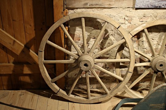 Old wooden wheels from grandfather's cart are stored in a rustic barn