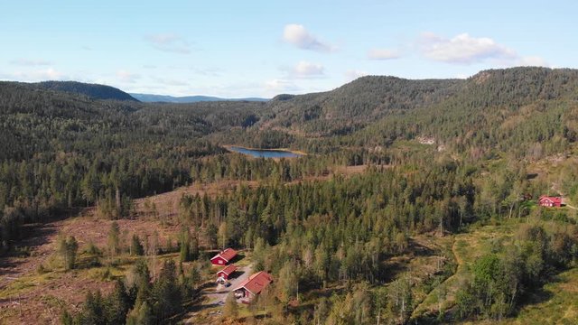 Aerial view over Heisetra cabins with a small lake and lots of pine trees and forest surrounding the cabins, in Kodal, Norway
