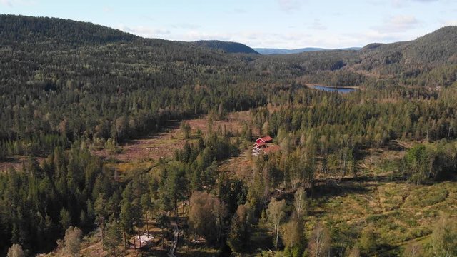 Aerial view over Heisetra cabins with a beautiful lake and lots of pine trees and forest surrounding the cabins, in Kodal, Norway