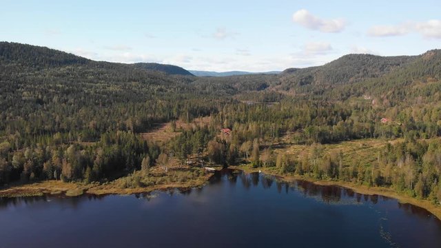 Aerial view over Heisetra cabins with a beautiful lake and lots of pine trees and forest surrounding the cabins, in Kodal, Norway