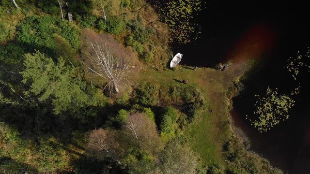 Aerial view over people at a small shore with a little rowboat in the forest by the Heisetra cabin in Kodal, Norway