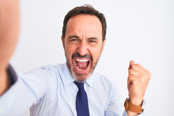 Middle age businessman wearing tie make selfie standing over isolated white background screaming proud and celebrating victory and success very excited, cheering emotion