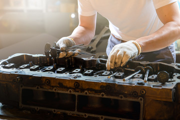 closed up of cylinder head and mechanic man holding valve and inspection cylinder head, Business...