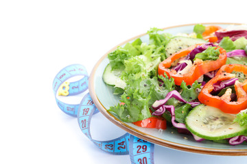 Plate with fresh salad and measuring tape isolated on white background