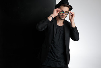 sensual young man fixing glasses in studio
