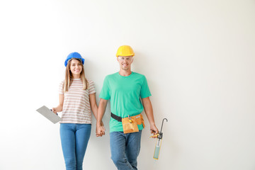 Happy young couple with tools on light background