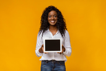 Smiling african woman demonstrating blank digital tablet screen