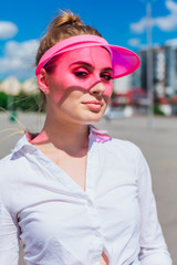 Portrait of an emotional girl in a pink cap visor and protective gloves for rollerblades and skateboarding.