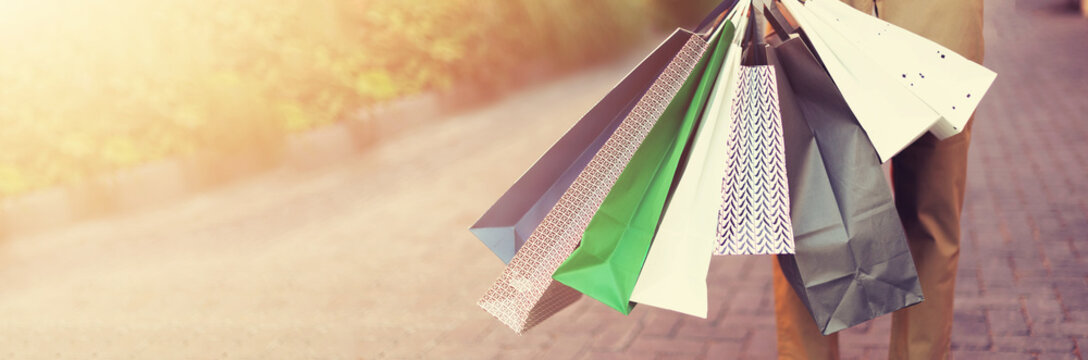 Sale, discount, black friday concept. Man with bunch of shopping bags. Copy space. Shopping mall and outlet