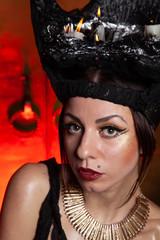 Evil stylish woman witch with big black hat on dark scary smoky background alone