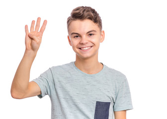 Portrait of happy teen boy showing one palm - 4 fingers, isolated on white background. Happy smiling child doing gesture of number Four. Series of photos count from 1 to 10.