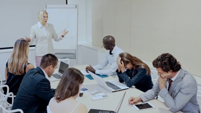 Unhappy business woman blaming subordinates for bad work on staff meeting at office