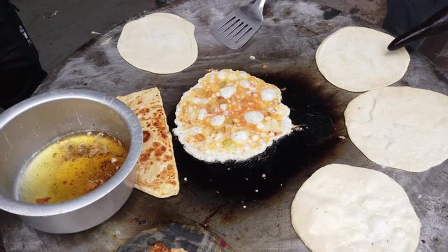 Preparation of Egg Paratha, a flatbread, originated from Indian subcontinent. Layers of cooked dough or anda parat is a healthy delicious snack with omelette stuffing with whole grain wheat flour 