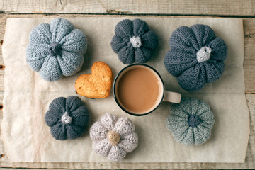 Autumn still life from handcrafted knitted pumpkin, cookie, mug of cocoa, coffee or hot chocolate on baking paper. Concept warm cozy home fall season comfort.