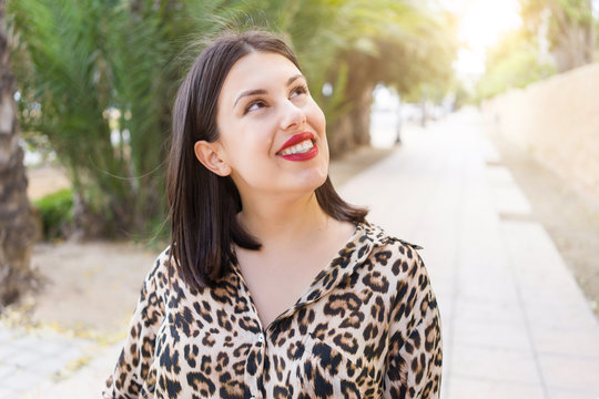 Young beautiful woman with red lips smiling happy at garden