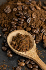 Wooden Spoon filled with coffee powder and coffee beans isolated on dark background