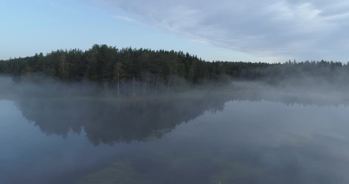 Drone shot of flying above a misty lake and forest in Finland.