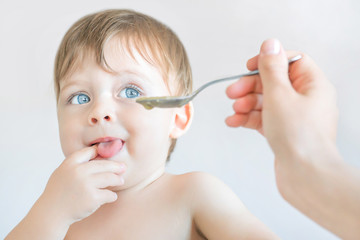 Feeding a blue-eyed blond baby with a spoon.
