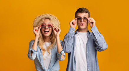 Young couple trying on trendy sunglasses, getting ready for vacation - obrazy, fototapety, plakaty