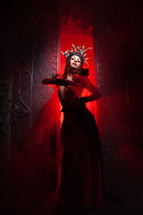 beautiful fashion witch woman with horns in the form of tree roots in a long luxurious dress on the...