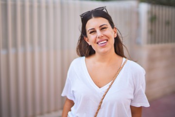 Young beautiful woman standing on the street smiling