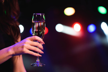 holidays, nightlife, drinks, people and luxury concept - beautiful young woman drinking champagne at party over lights background.