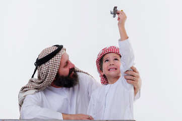 Arabic grandather and grandson playing together indoors using toy aircraft.