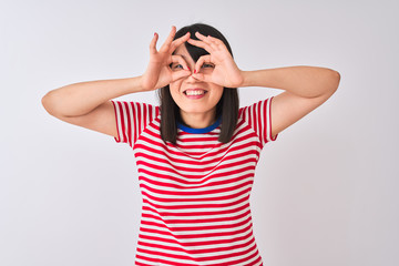 Fototapeta premium Young beautiful chinese woman wearing red striped t-shirt over isolated white background doing ok gesture like binoculars sticking tongue out, eyes looking through fingers. Crazy expression.