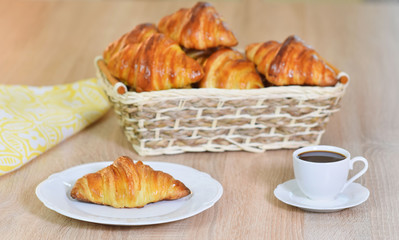 Coffee with a croissant on a plate.
