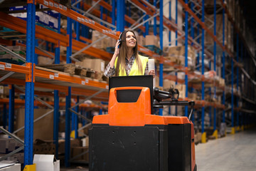 Professional warehouse worker with headset communication equipment driving forklift and relocating...