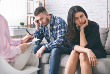 Young couple sitting separately at family counselor office