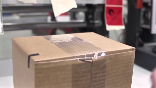 Worker Putting A Sticky Label Reading Flammable Liquid On A Cardboard Box