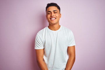 Young brazilian man wearing t-shirt standing over isolated pink background with a happy and cool...