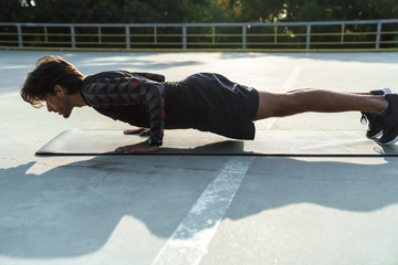 Photo of athletic slim man doing exercises on mat while working out