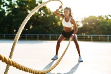Photo of african american strong woman doing workout with battle ropes
