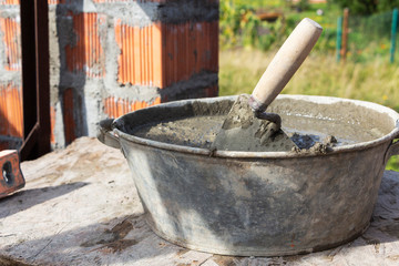 Trowel in the mortar, a container of cement, construction concept.