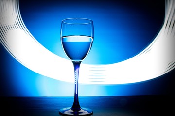 wine glass with water on a blue background with luminous lines