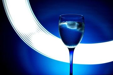 wine glass with water on a blue background with luminous lines
