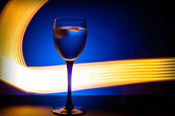 wine glass with water on a blue background with luminous lines