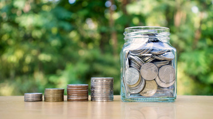 Growing coins and coin jar on wooden floors. Financial concepts. Saving money for investment.
