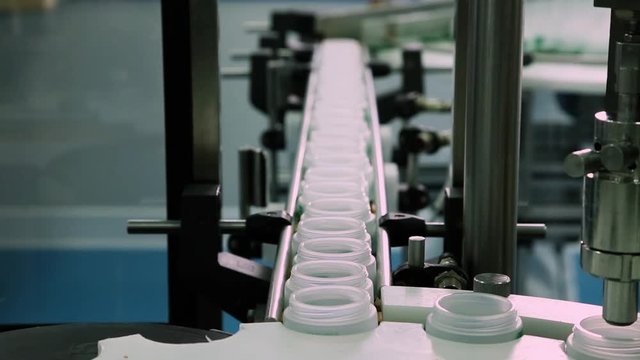 Cosmetics Manufacturing Industry Belt Conveyor. Sealing Face Cream Jars