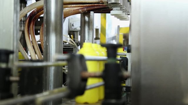Cleaning products manufacturing. Yellow bottles on the belt conveyor. Production line