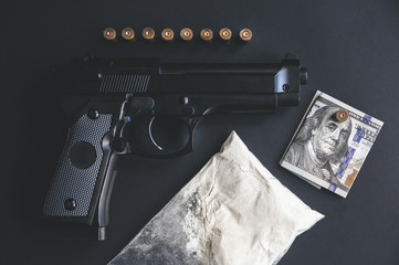 Gun with bullets lying on the table. Criminal problems. Drugs and money on black background....