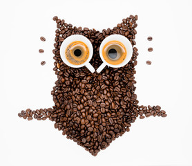 Owl made of roasted coffee beans and two cups. A symbol for night people.